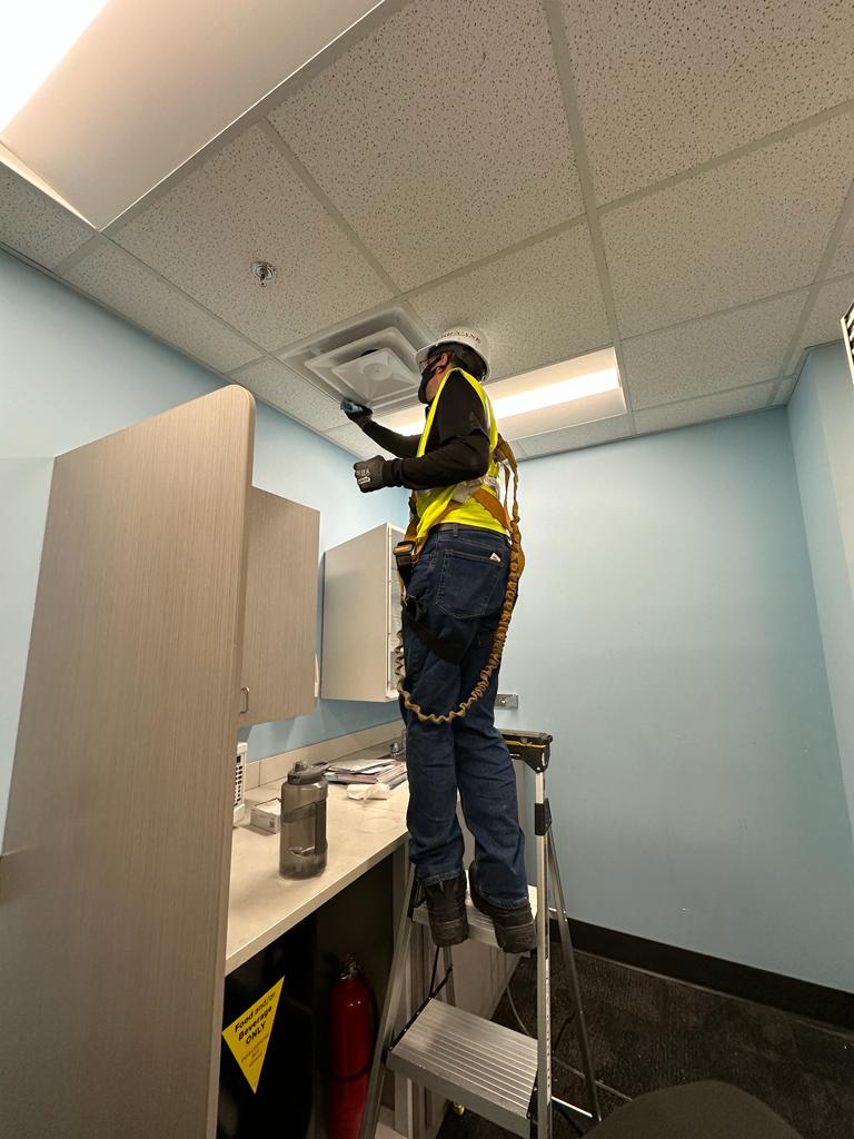 Facility break room — ceiling diffuser cleaning with harness and tether