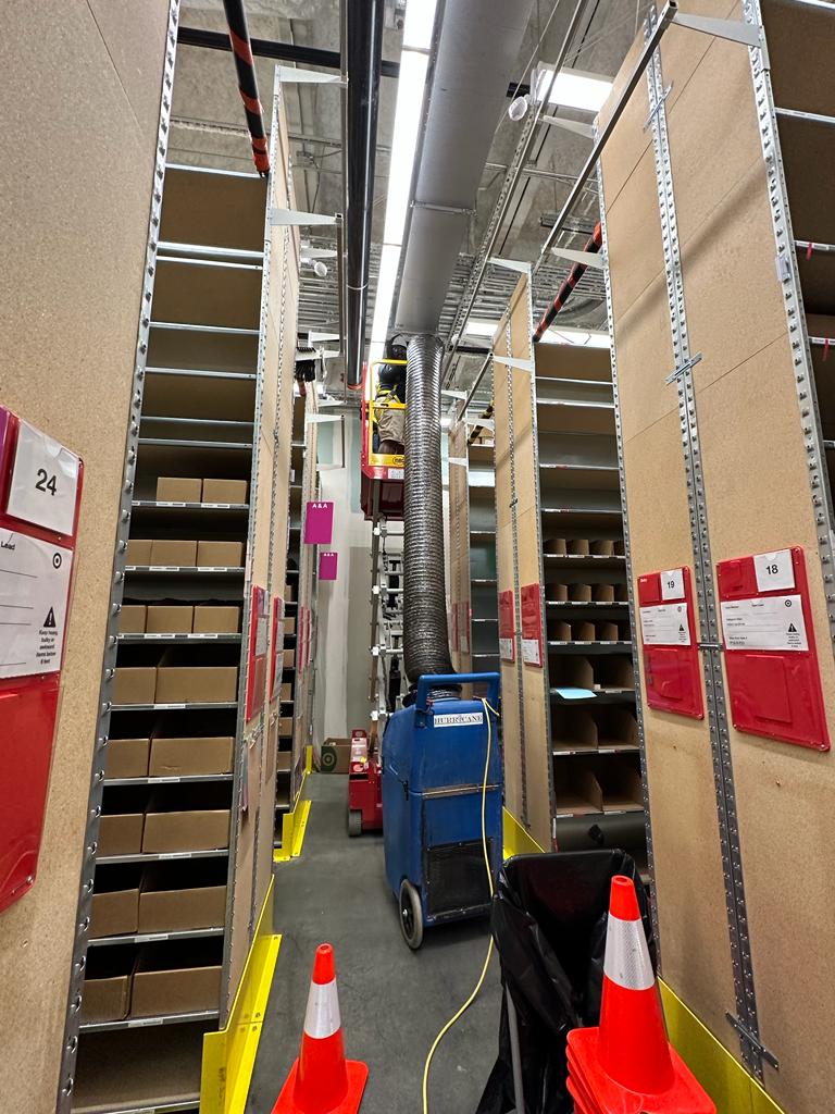 Storage facility stockroom — aisle duct cleaning with cone-protected work zone