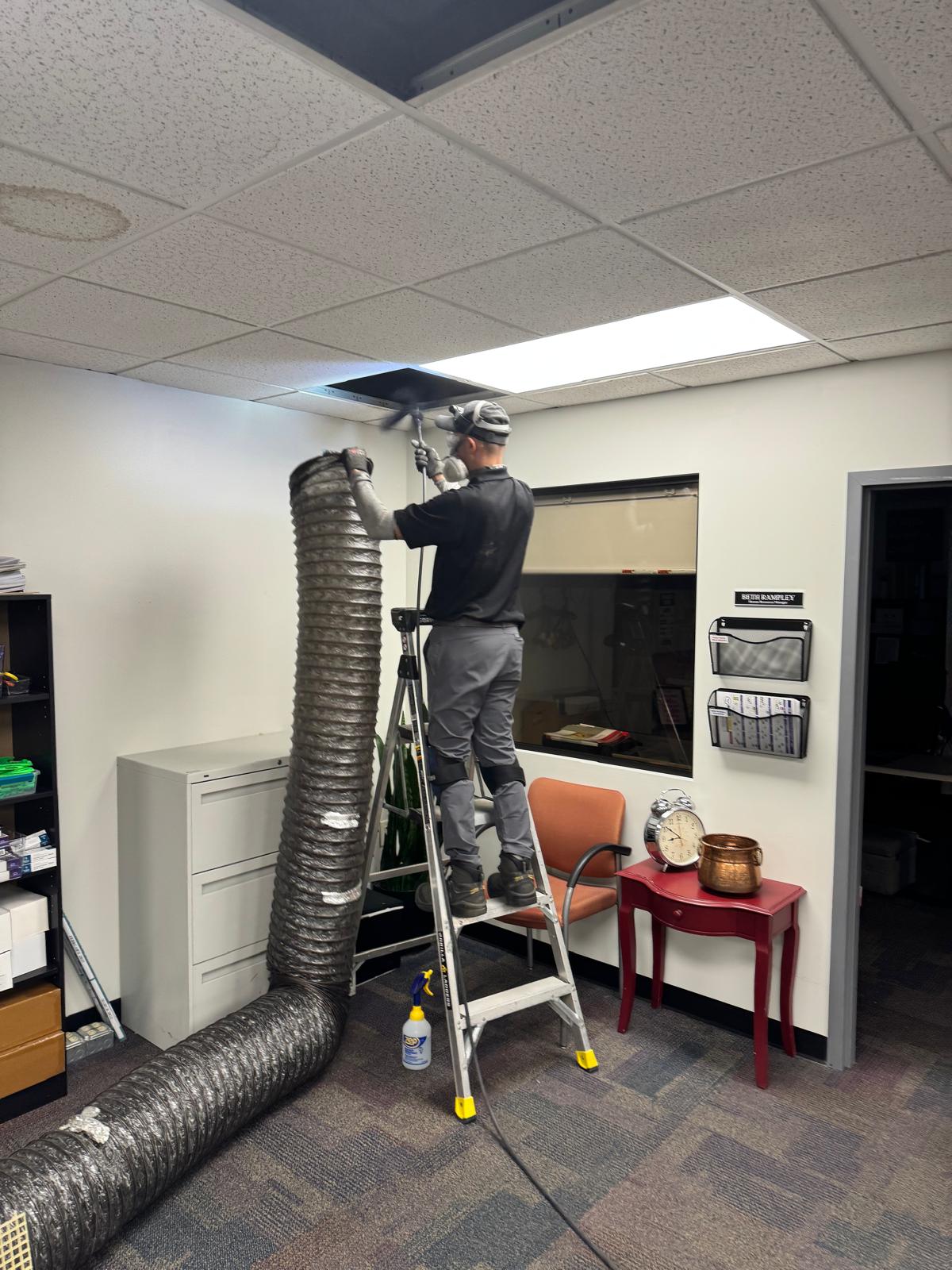 Dealership HR office — duct access with flex hose to negative-air machine