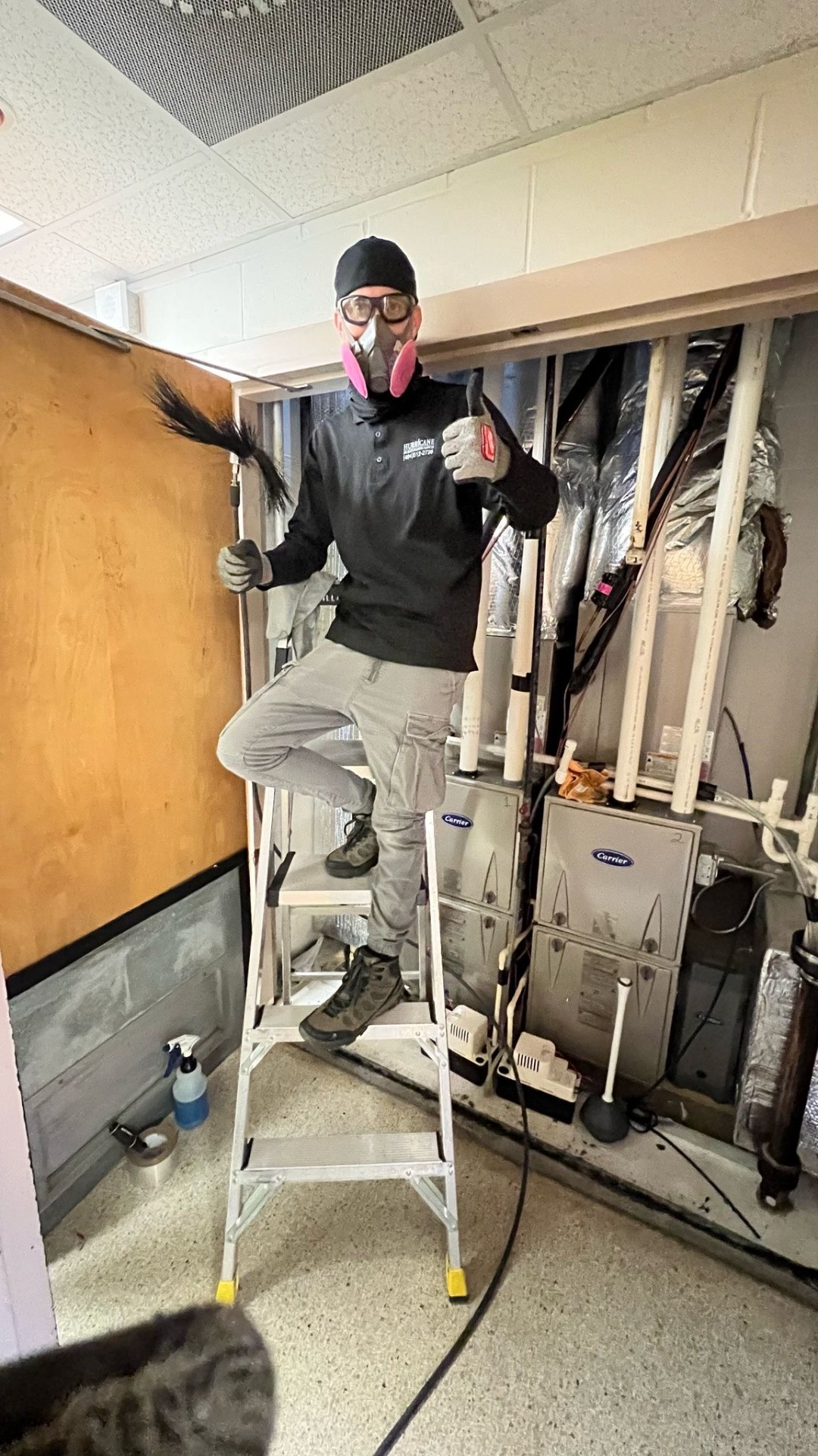 Fire station mechanical room — Hurricane tech in full PPE servicing dual Carrier furnaces with agitation whip and HEPA vacuum