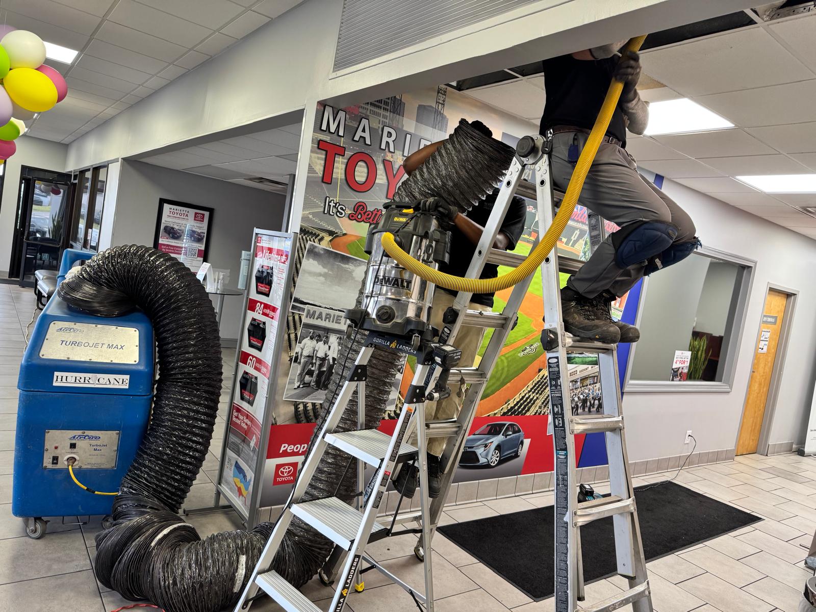 Dealership lobby — HEPA negative-air rig and source-removal cleaning at the entry