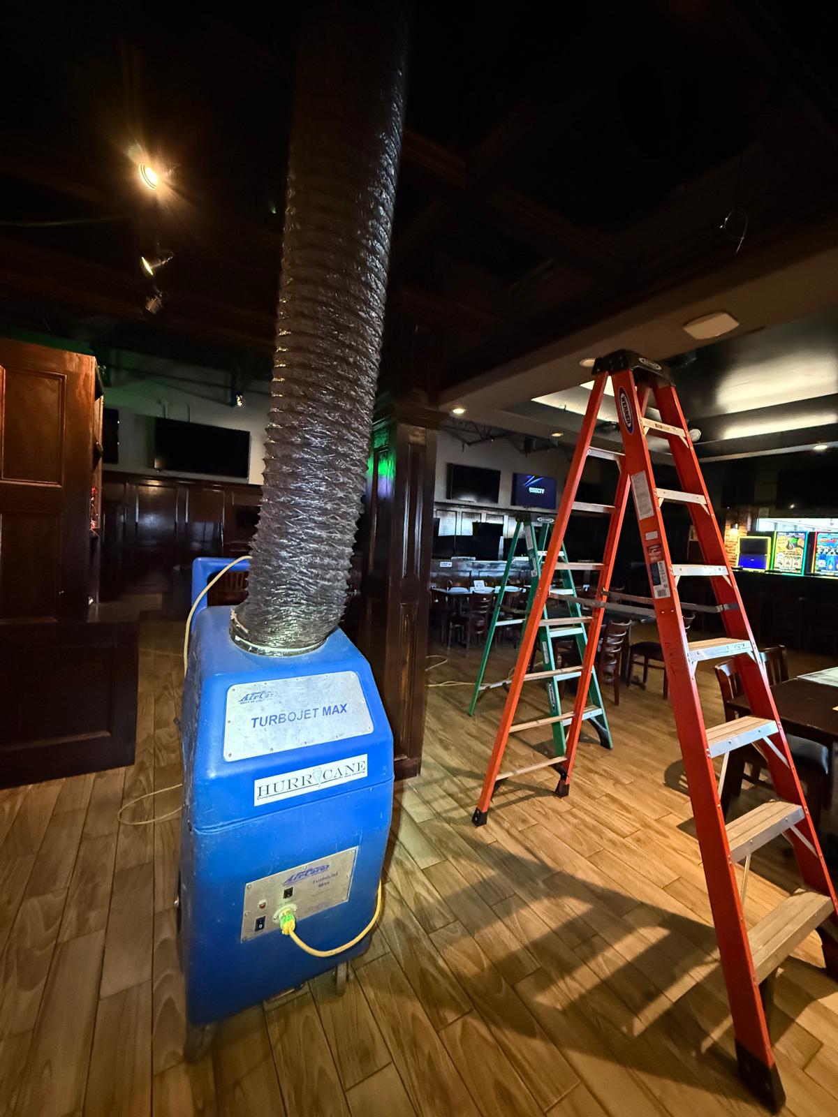 Club floor — Hurricane TurboJet Max negative-air machine staged between the bar and dining area