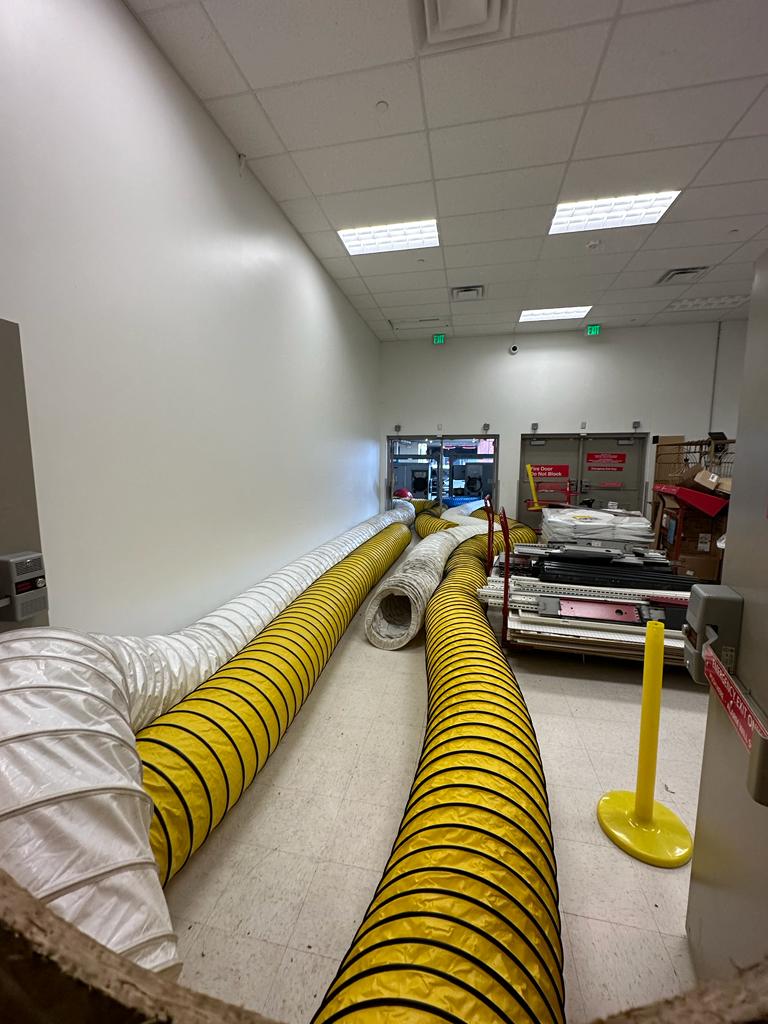 Retail negative-air staging — large-diameter flex ducts routed through the back corridor