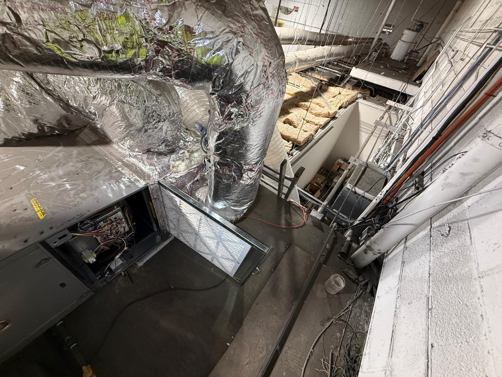 Factory mezzanine — air handler filter rack open with insulated flex duct connections exposed