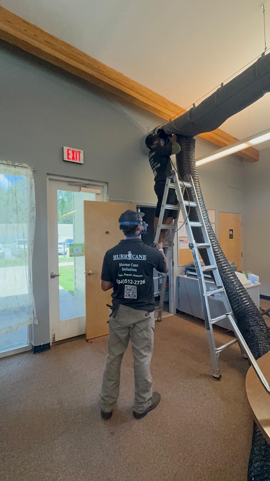 Commercial Air Care technicians cleaning overhead office ductwork from ladders