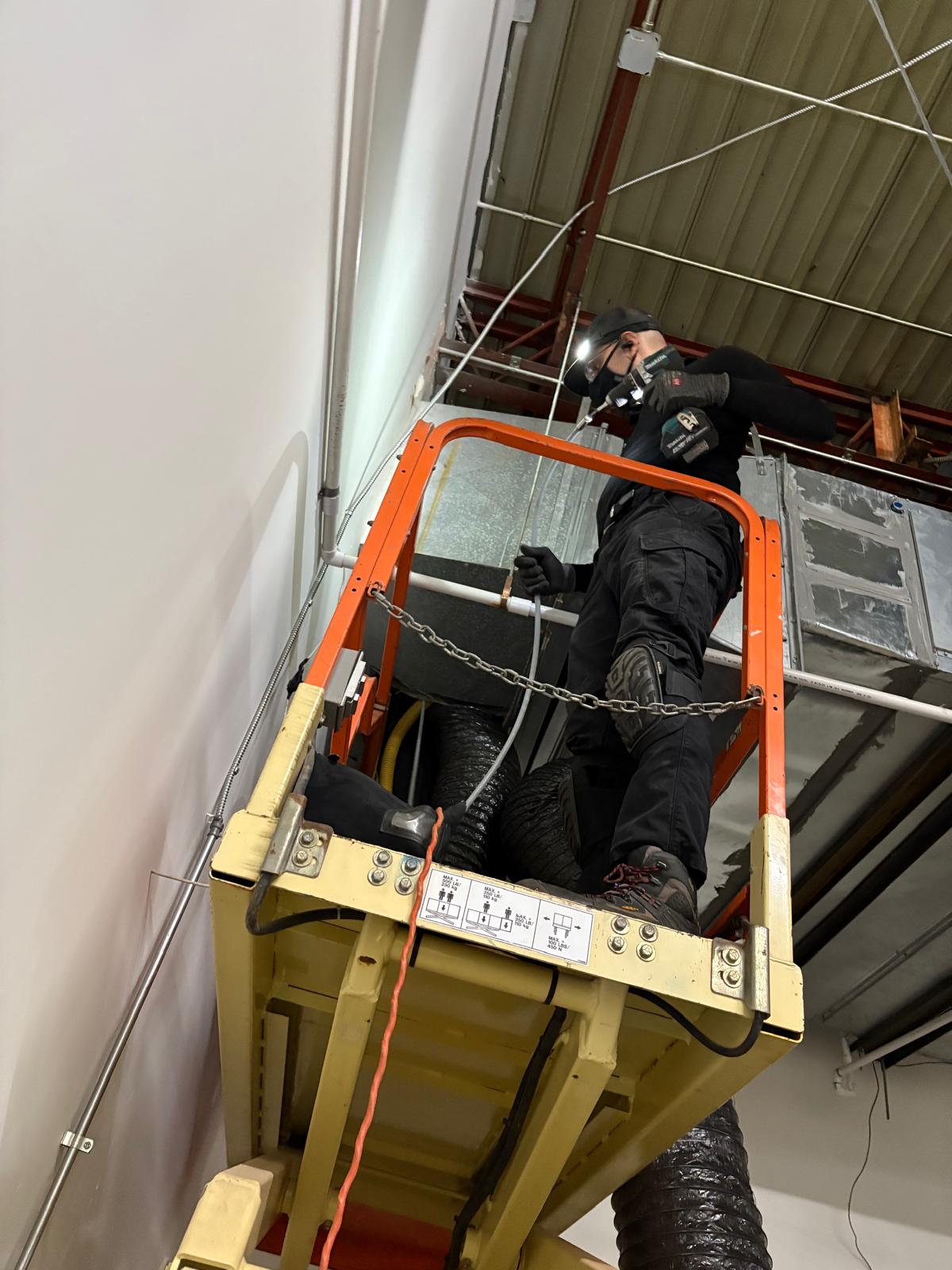 Warehouse high-bay — scissor-lift access to overhead supply duct
