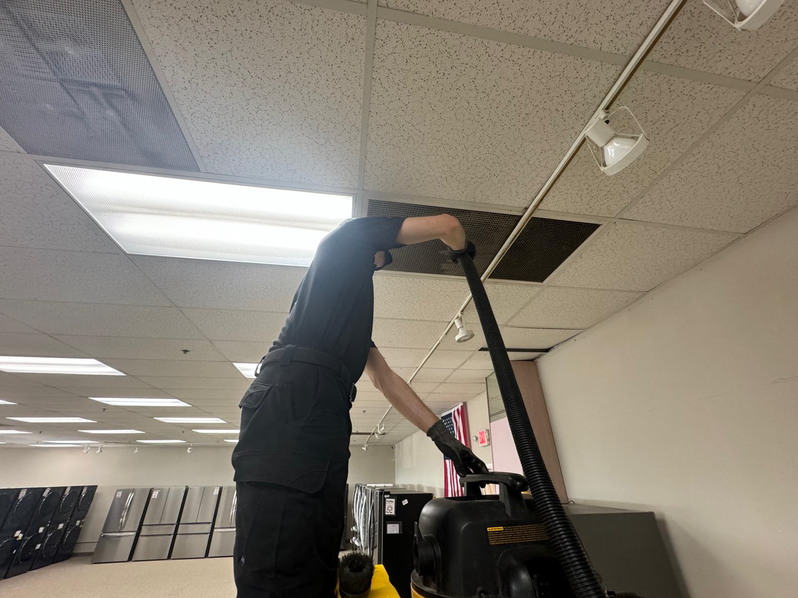 Appliance showroom — ceiling diffuser cleaning with HEPA vacuum on the sales floor