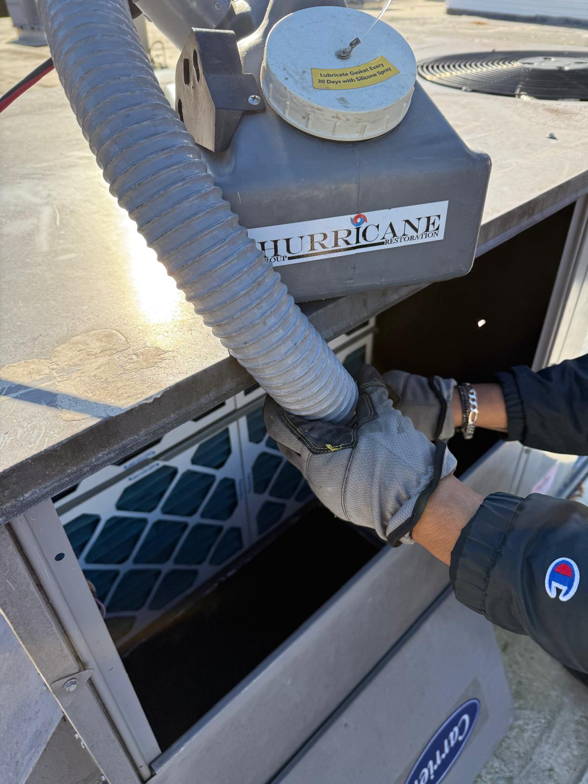Carrier RTU — HEPA negative-air hose connected at the filter access panel