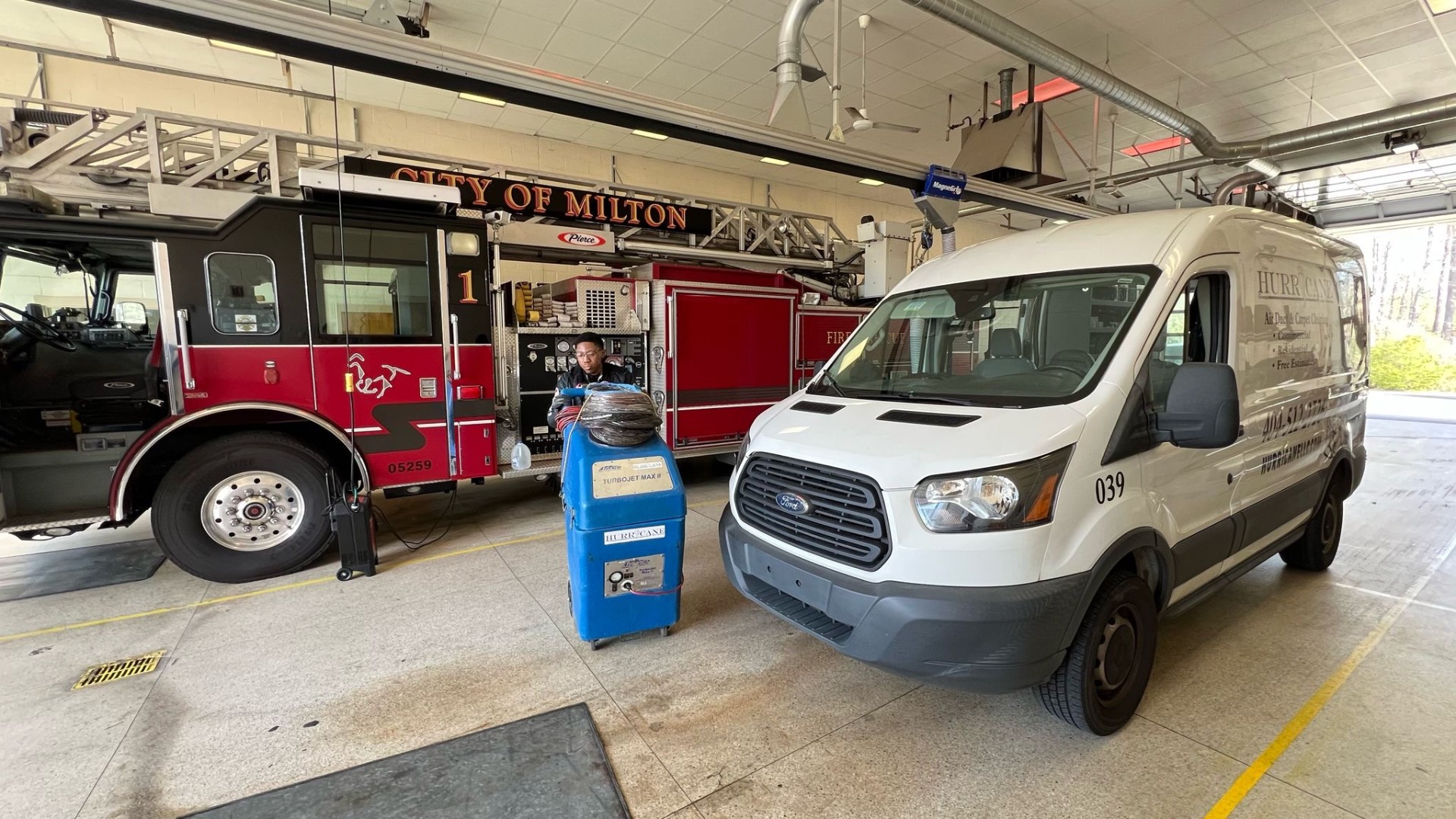 Fire station apparatus bay — negative-air equipment positioned between ladder truck and service van during overnight HVAC cleaning