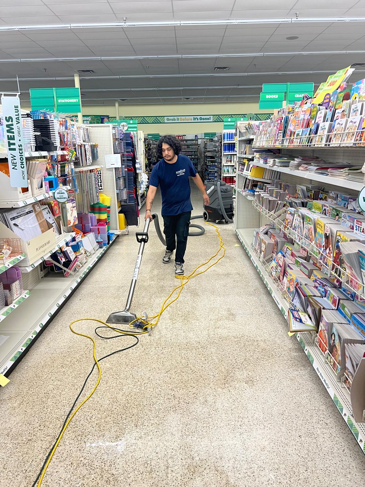 Dollar Tree water extraction — technician running a self-contained extractor down the stationery aisle after a store flood