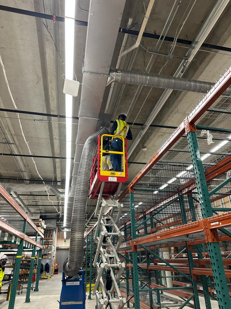 Distribution center — spiral duct source-removal cleaning over racking
